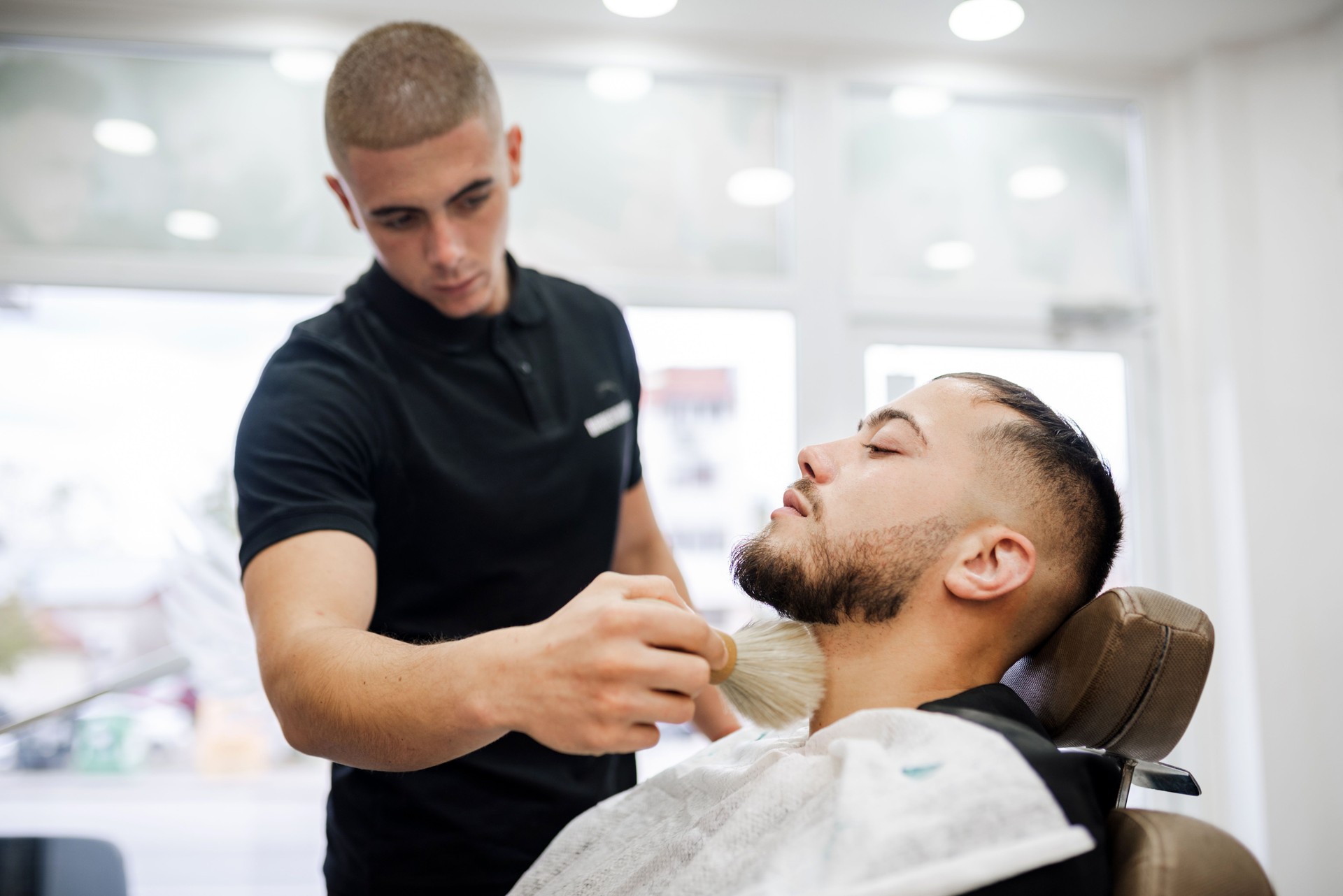 Barber shaves the beard of the client in a barbershop